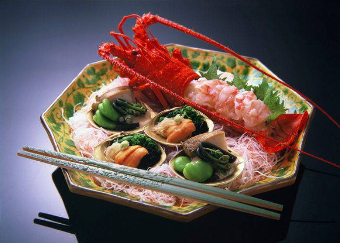 A luxurious lobster kaiseki meal, showing off a fresh lobster and small dishes.